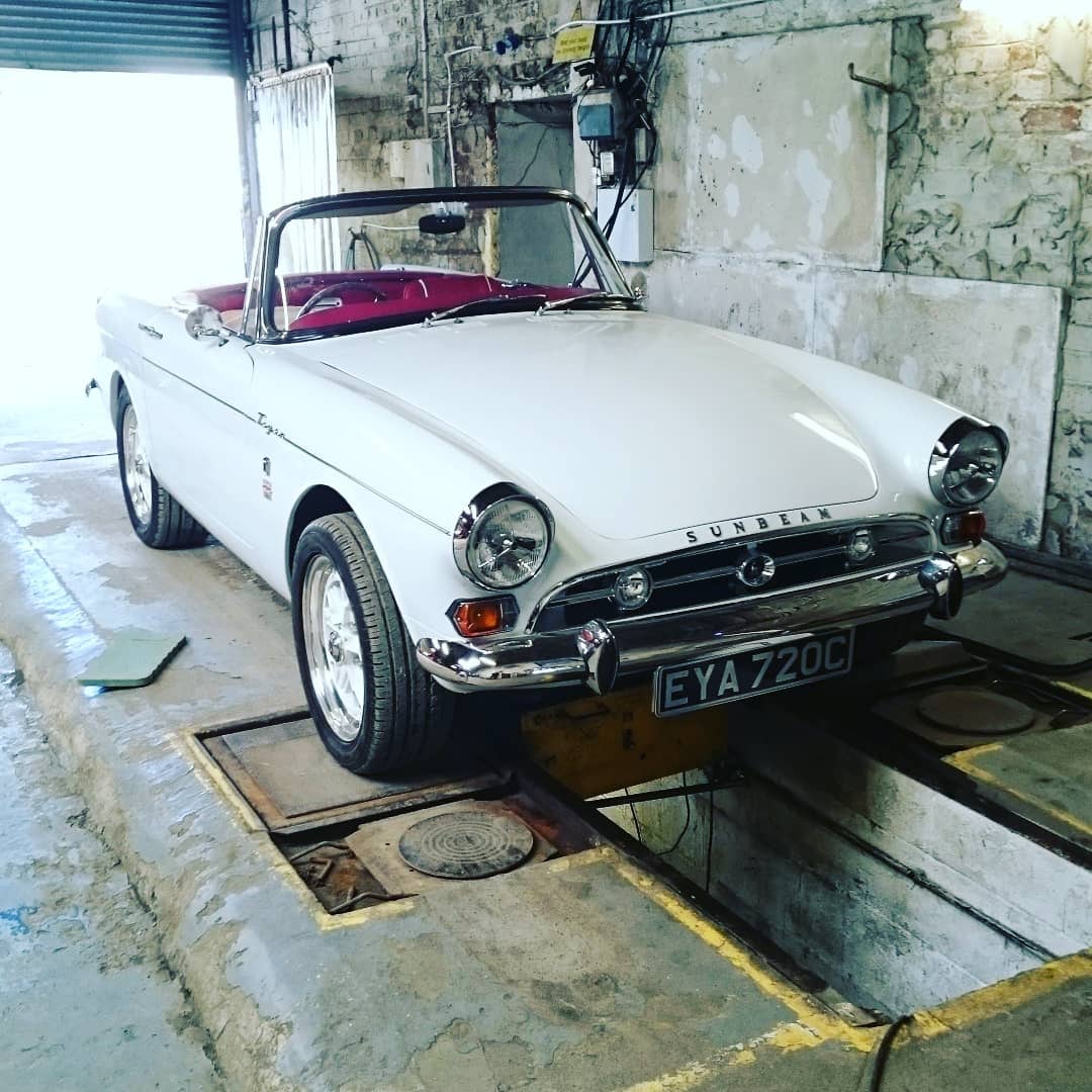 White Sunbeam convertible over the inspection pit inside the workshop