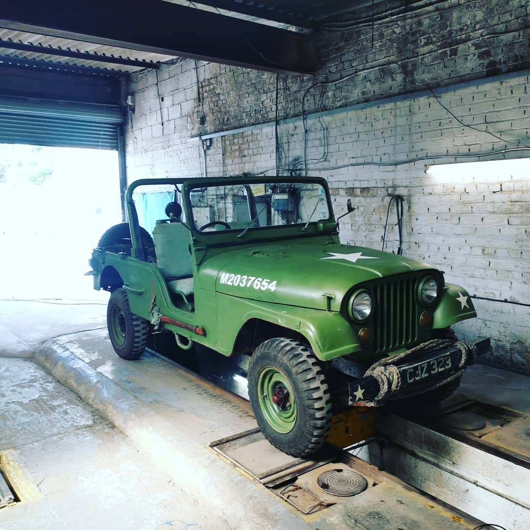 Green Jeep above the inspection pit at the garage